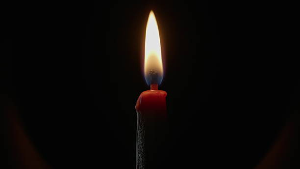 istock Closeup candle casting light in shadowed space. Gentle flame dancing on dark 2237598755