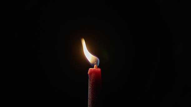 Closeup candle flame moving inside dark room with no daylight. Fire swaying