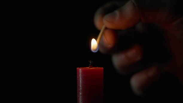 istock Match lighting single candle isolated on black background. Wick lights up flame 2237599741
