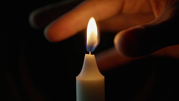 istock Fingers squeezing candle fire on black background closeup. Person snuffing wax 2237601019