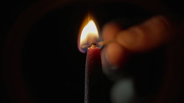 istock Fingers match sparking candle using match black background closeup. Bright flame 2237601145