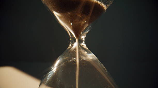 istock Gold sand grains running inside hourglass measuring time in countdown closeup. 2237605544