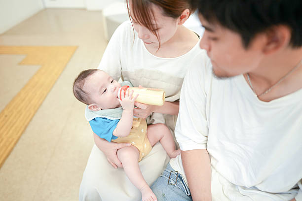 istock A man and woman are holding a baby while feeding him 2237609662