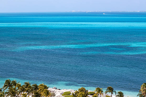 Beach with view to the sea and clouds in the sky. The caribbean sea has colours like blue, green and turquoise.
