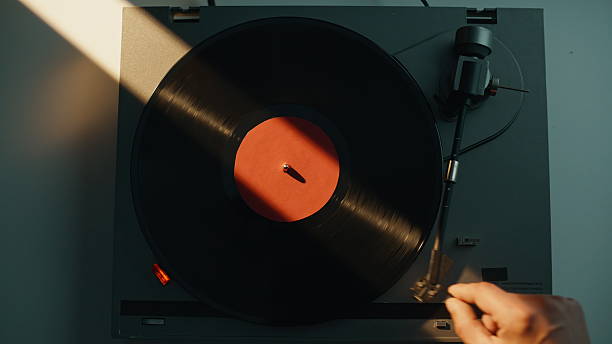 istock Hand putting gramophone needle on black vinyl disc in evening light closeup. 2237611436