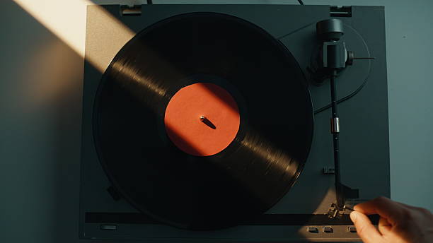 istock Man taking vinyl disc from gramophone at home closeup. Hand turning off play 2237611485