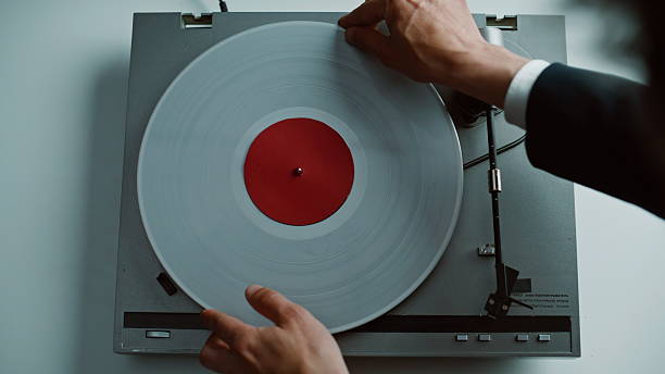 Hands putting vinyl disc at vintage gramophone placed on table closeup top view