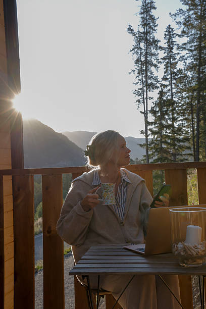 istock Mature woman uses mobile phone on deck at sunrise 2237619155