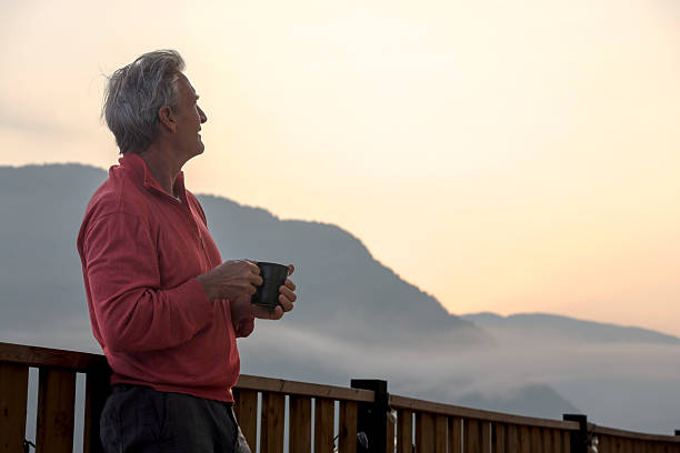 istock Mature man watches sunrise from chalet deck 2237619187