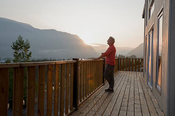 istock Mature man watches sunrise over mountains from deck 2237619197