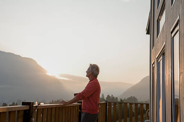 istock Mature man watches sunrise over mountains from deck 2237619198