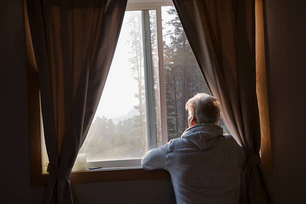 istock Mature man watches sunrise through bedroom window 2237619201