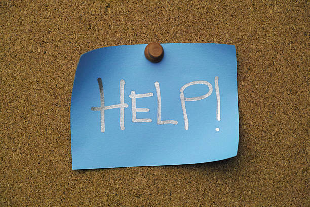 istock Blue paper note pinned to a cork message board, with the single word 'HELP !' written on it. 2237633117