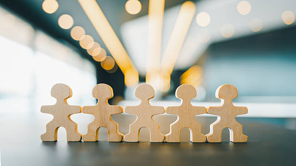 istock Wooden human figures standing in a row on a desk, symbolizing teamwork, unity, collaboration, and strong connection in a modern business environment with blurred office background. 2237639522