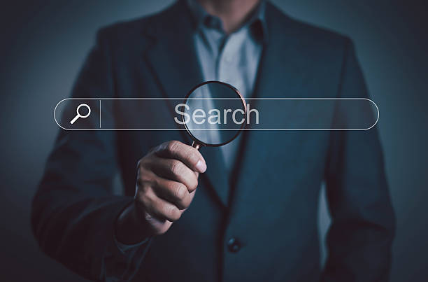 istock Businessman holding magnifying glass over virtual search bar, symbolizing internet research, SEO optimization, data analysis, online marketing, and digital information concept. 2237657370
