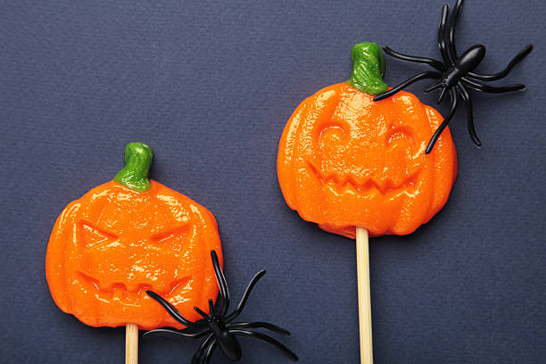 istock Halloween lollipops shaped like a pumpkin with decorative spider on dark blue background. 2237659208