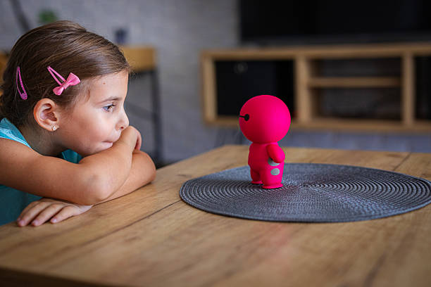 Child communicating with artificial intelligence toy robot in living room