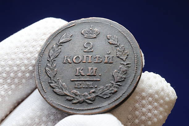 istock An old coin featuring the denomination 2 kopecks with a crown and laurel wreath design, held in a gloved hand against a dark background 2237667487