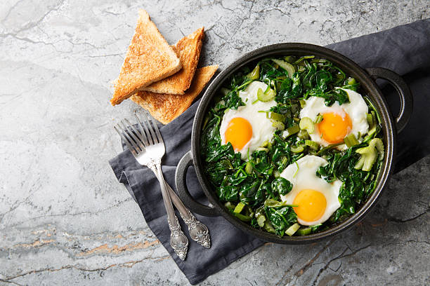green shakshuka is healthy, one-pan and full of fresh herbs, spinach, and eggs closeup on the pan. Horizontal top view