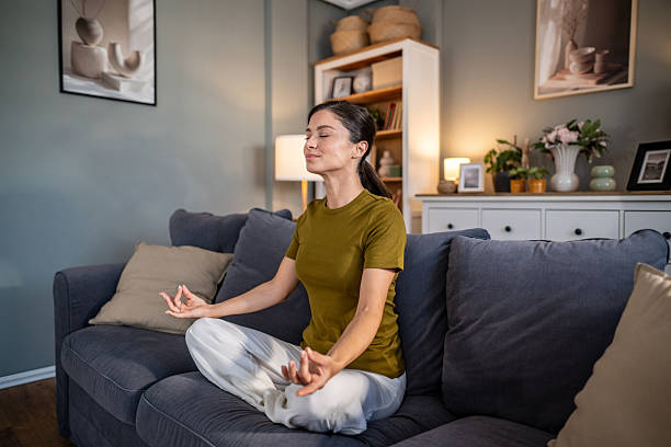 istock Woman meditating on couch at home practicing yoga 2237684488