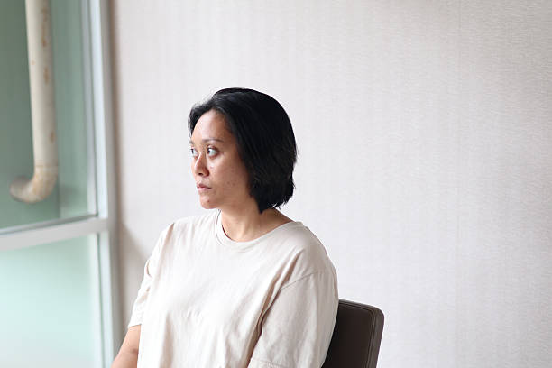 istock Young asian woman sits looking stressed, sad, and unhappy. She may be experiencing depression. with copy space 2237684798
