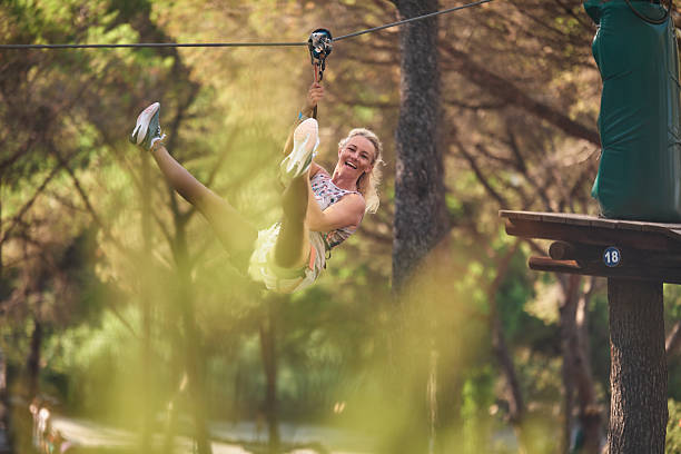 istock Happy woman actively zip lining through summer forest adventure park 2237686593