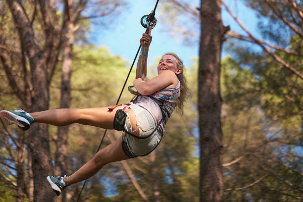 Woman ziplining through a forest, experiencing exhilaration and fun.