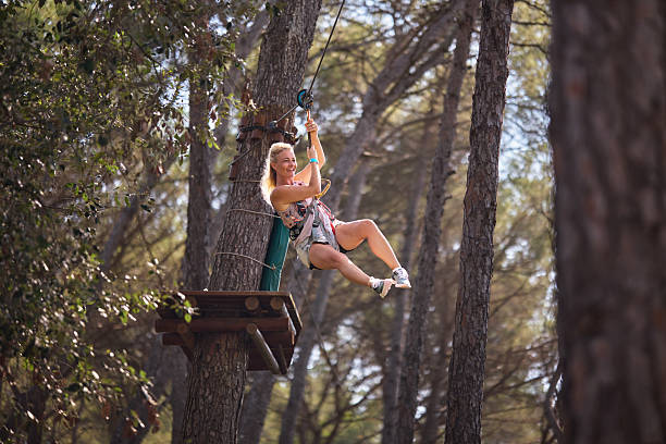 Woman smiling while ziplining through a forest adventure park.