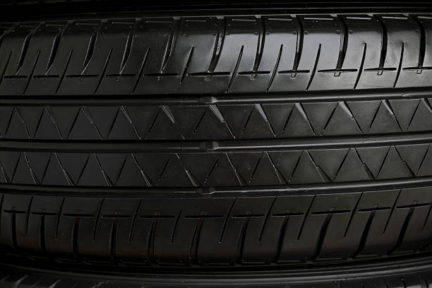 Close up of a grey luxury wheel of car , close up of the rear side of a black luxury car parked on an open road , Automotive concept