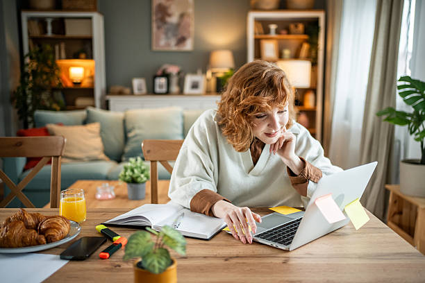 istock Redhead woman having breakfast and working on laptop at home 2237696185