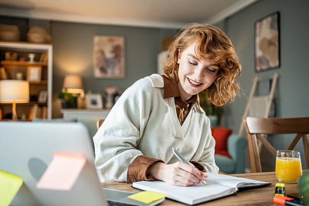 istock Young woman writing notes in notebook at home 2237696197