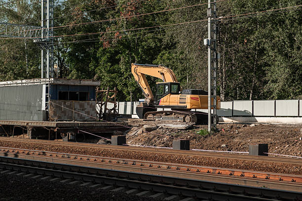 istock Excavator at a Railway Construction Site Near a Track Surrounded by Trees in the Late Afternoon Light 2237696520