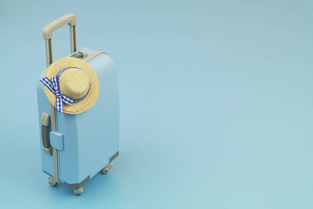 Blue travel suitcase with beach hat and on blue background. Copy space for text. Tourism and travel concept.