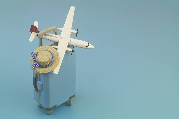 istock Travel suitcase with beach hat and airplane model on blue background. 2237697530