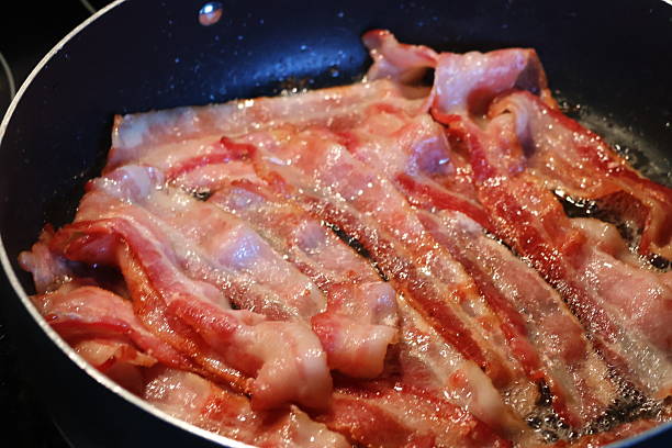 A strip of fried bacon is lifted from a pan, July 9, 2011, in Columbus, Mississippi. Bacon is a type of salt-cured pork created from the meat of pigs. The most common form of bacon is side bacon, also known as streaky bacon. This type of bacon comes from pork belly. (Photo by Carmen K. Sisson/Cloudybright)
