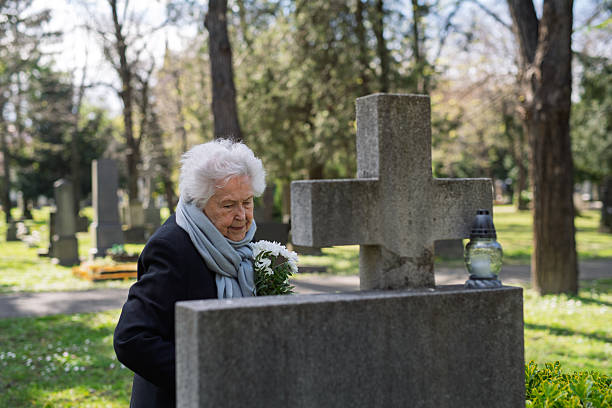 istock Elderly woman visiting a grave on All Saints Day. 2237699064