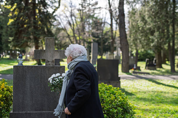 istock Elderly widow bringing flowers to a grave at cemetery. 2237699148