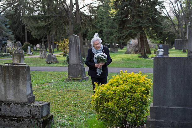 istock Elderly woman visiting a grave on All Saints Day. 2237699163
