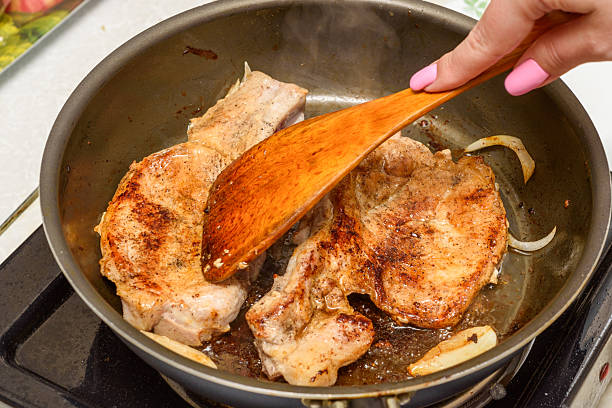 Pressing meat with a wooden kitchen spatula while frying. Home cooking.