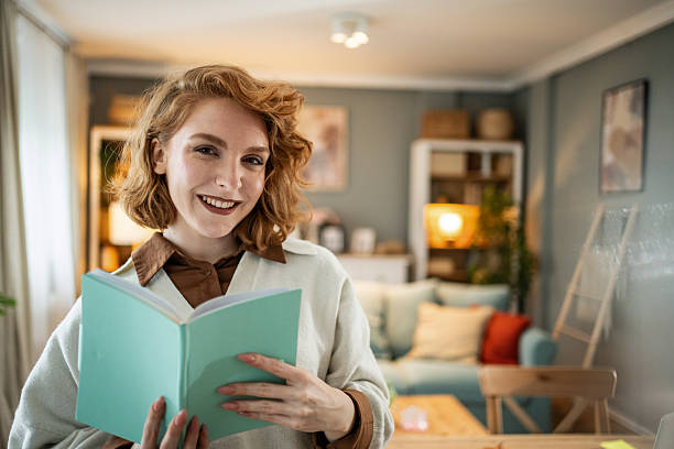 istock Young woman smiling holding book at home 2237704444