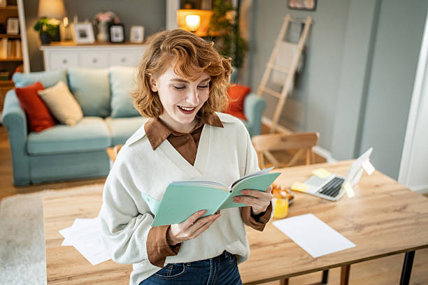 istock Young woman smiling and reading a book in home office 2237704471