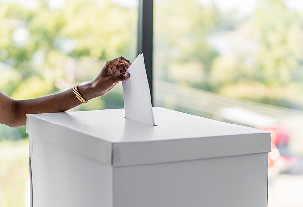 Person casting a vote into a ballot box, emphasizing civic duty and democratic participation in an important election