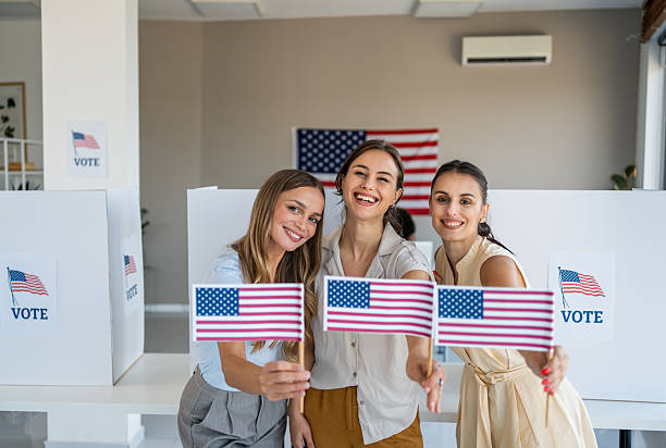 Group of women actively participating in the election process, holding US flags and wearing vote buttons