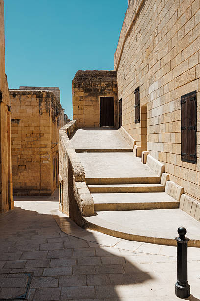 istock Sunlit Maltese Stone Staircase Beside Beige Limestone Walls Under a Clear Blue Sky 2237722462