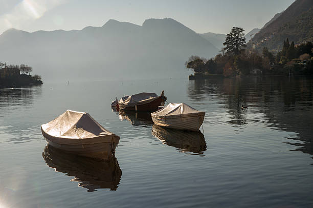 Sheltering boats nexto shore of lake Como and amazing landscape ( a little) foggy landscape on lake Como. At right somee village on lake . In distance Europeamn Alps