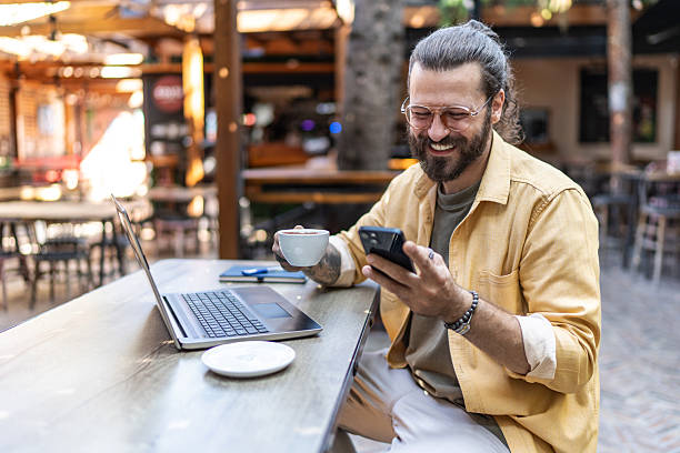istock Man drinking coffee and using phone at outdoor cafe 2237740091