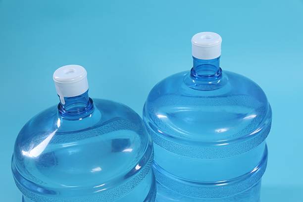 Cooler bottles with water on light blue background, closeup