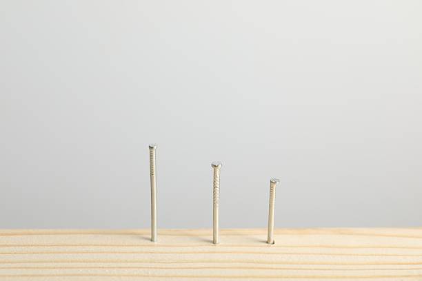 istock Metal nails in wooden plank on light grey background, closeup 2237749029
