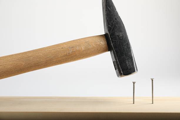 istock Hammering nail into wooden plank on white background, closeup 2237749147
