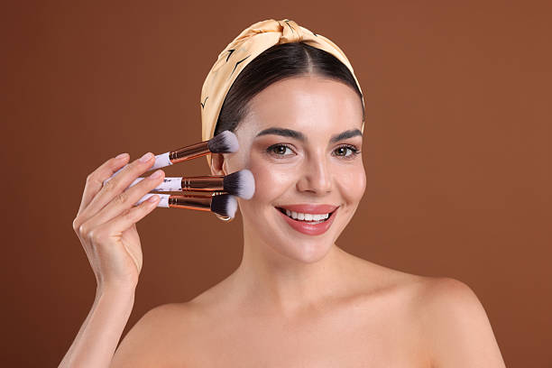 istock Beautiful woman with makeup brushes on brown background 2237751018